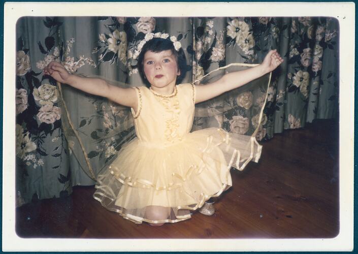Girl wearing yellow fairy dress with arms outstretched.