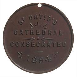 Round copper medal with raised text.