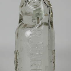 Clear glass bottle with raised inscription.