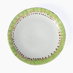 White tea cup saucer. Green, pink and gold painted decorative rim.