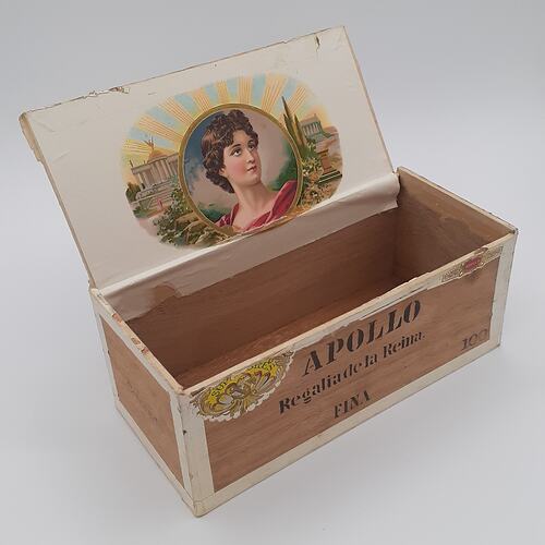 Wooden box with lid open, lid has a womans picture pasted inside.