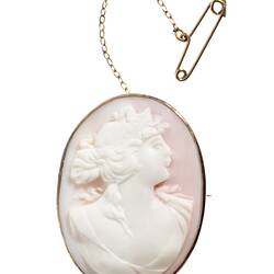 Oval white brooch with cameo of female bust in gold setting with safety chain.