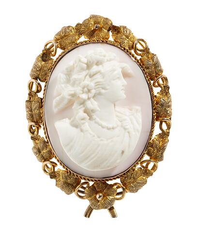Oval brooch with gold framing white cameo relief woman facing right. Frame is gold leaves and tendrils.