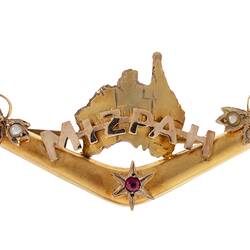 Back of gold boomerang with a map of Australia behind the words 'Mizpah'. Has seed pearls and a small ruby.