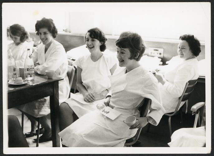 Women wearing white uniforms casually sitting in tea room.