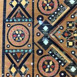 Detail of timber inlay jewellery box. Geometric patterns in dark and light light brown, blue, yellow, white and red.