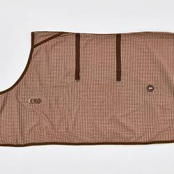 Rectangular woollen horse rug, brown and white check. Brown fastenings and leather straps. Folded, left side.