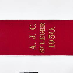 Back of red ribbon sash with gold fringe.