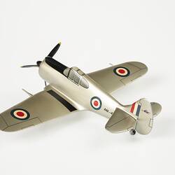 Back view of model aeroplane, silver with a black propeller and wheels.