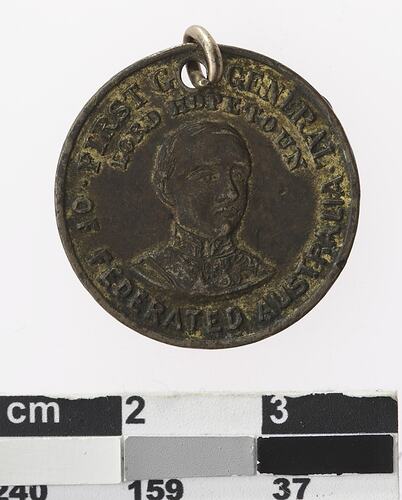 Round medal with portrait of a man and text surrounding.