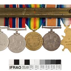 Group of five medals mounted on a bar, with multicoloured ribbons attached to top of medals.