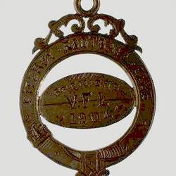 Gold medal with engraved football shape within a circle. Scroll detail above.