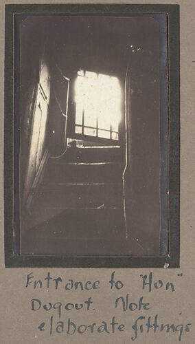 View from the bottom of a staircase, looking up towards an open window.