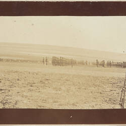 Rows of servicemen standing in formation on right, flag on left, hill in background.
