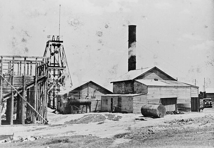 Gold mine with ore bins, poppet head, winding house and boiler house.
