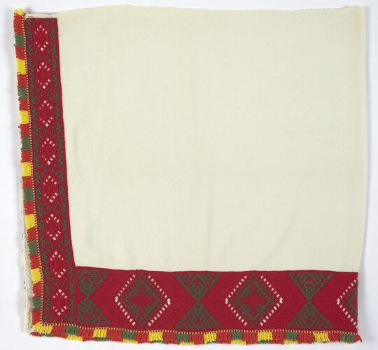 Corner of cream fabric with brightly coloured border.