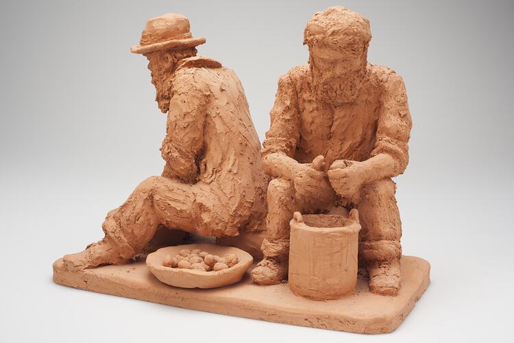 Clay sculpture of men peeling potatoes.
