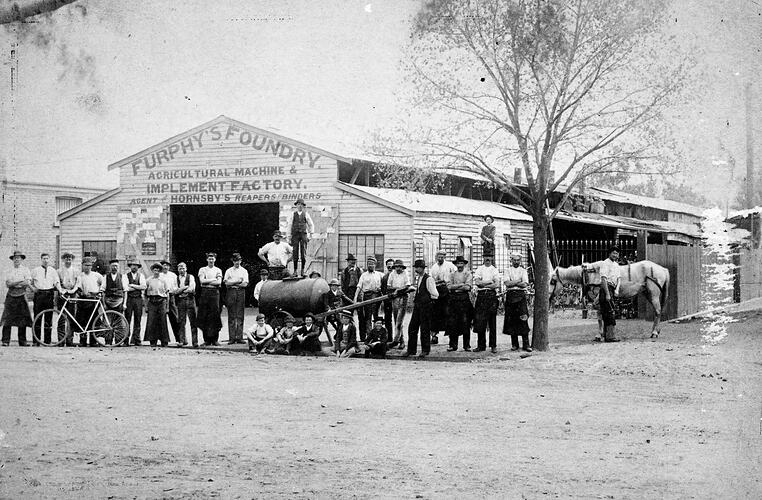 Workers in front of Furphy 's Foundry building. There is a water cart and horses.