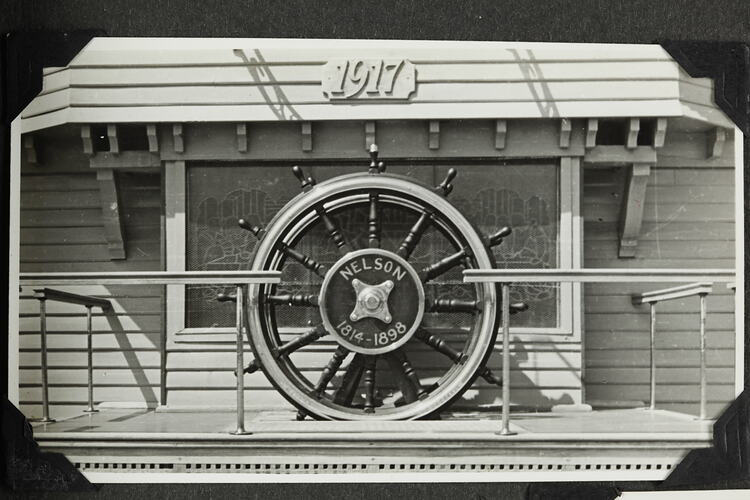 Ship wheel on podium with hand rails.
