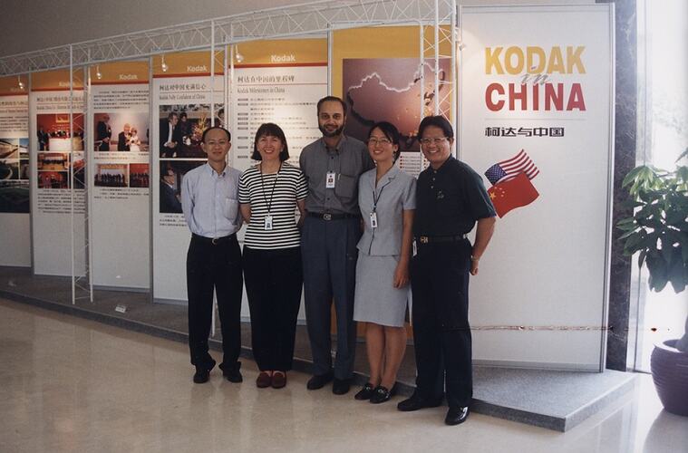 Five people posing in front of exhibition panels.