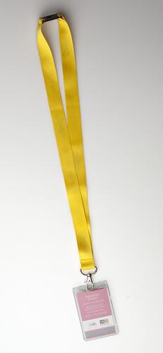 White card pass in plastic with yellow neck lanyard.