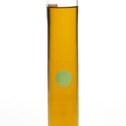 Cylindrical glass jar with yellow liquid. Two labels affixed, sealed at top.