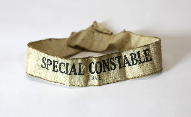 Cream cloth armband with printed inscription.