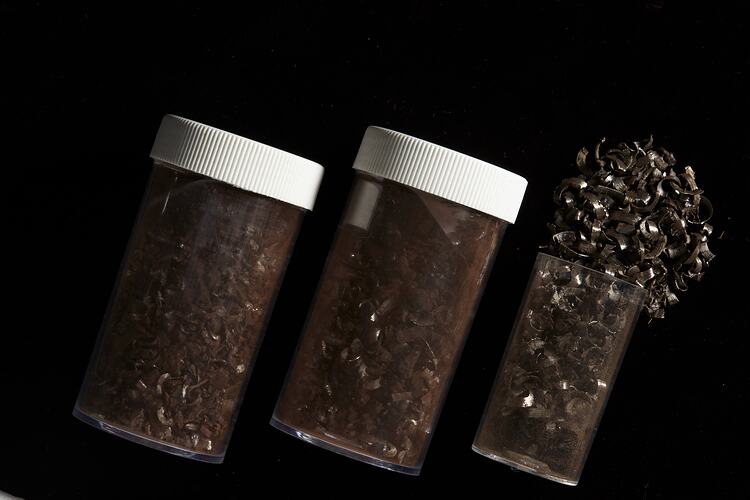 Thre vials, two sealed, one with rock material spilling out.