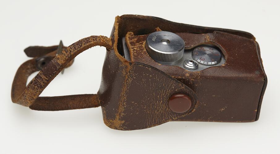 Miniature metal camera in brown case.