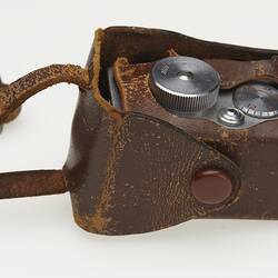 Miniature metal camera in brown case.