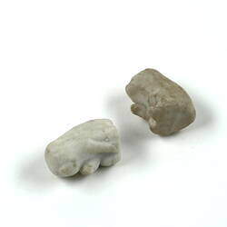 Two white animal figurines, lying down.