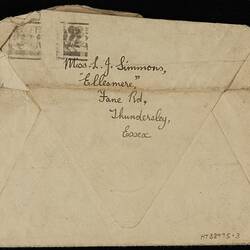 Back of cream envelope, opened, with handwritten text in black ink. Black ink stamp at top left.