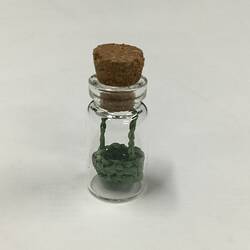 Miniature basket in glass phial with cork stopper.