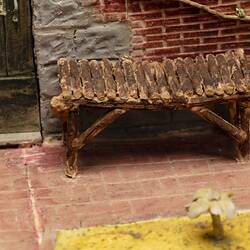 Model of red brick cottage and garden made from icing. Door and bench seat detail.