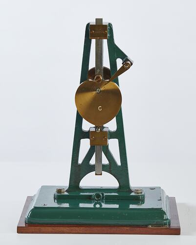 Metal model with green painted frame with metal heart shape and upright rod.