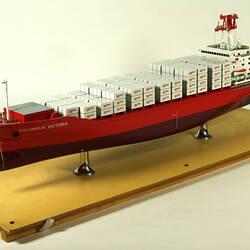 Container ship with red hull three quarter view.