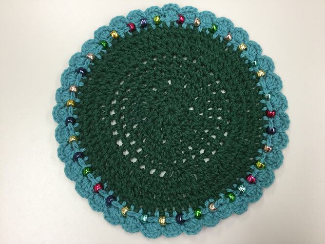Circular crocheted mat with beaded, scalloped edge,