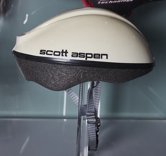 White bicycle helmet with grey padding and strap. Black text.