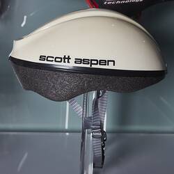 White bicycle helmet with grey padding and strap. Black text.