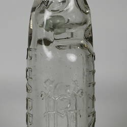 Clear glass bottle with raised inscription.