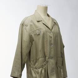 Large beige coat with elasticised pockets. Three quarter view.