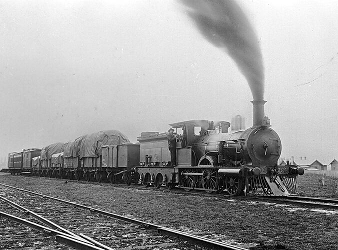 [F-class steam locomotive hauling passenger carriages and goods trucks, Waubra, 1910.]