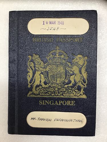 Blue passport cover with gold printed coat of arms. White strip at top and bottom.