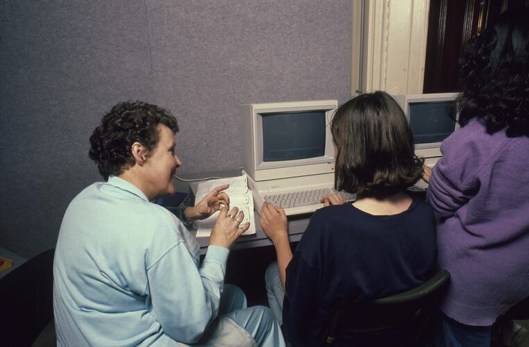 A teacher and students working in front of a computer.