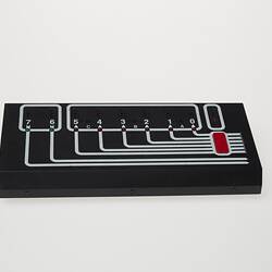 Rectangular black plastic computer control. White lines and lights on top.