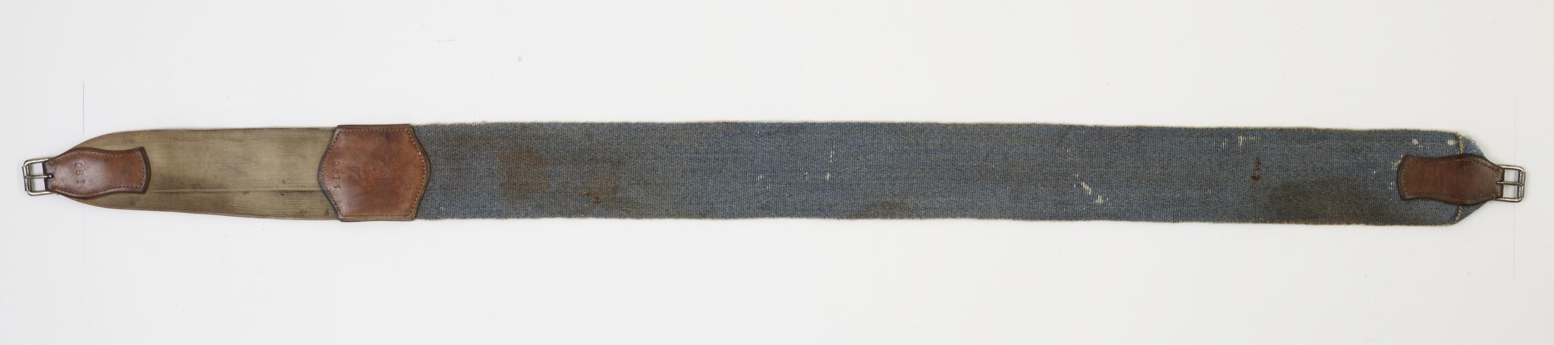 Girth strap is blue hessian with dirty white elastic and leather at join of materials and near buckles.