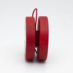 Red yo-yo with white cross. Red string.