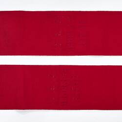 Back of folded red ribbon sash with gold fringe.