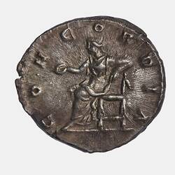 Roughly round coin. Seated figure facing left extending a patera with her right hand and resting her left elbow on the back of a chair. Text around.