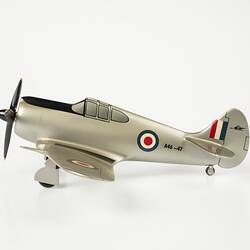 Model aeroplane, silver with a black propeller and wheels. Left profile.